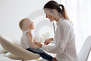 Pediatrician examining baby boy. Doctor using stethoscope to listen to kid