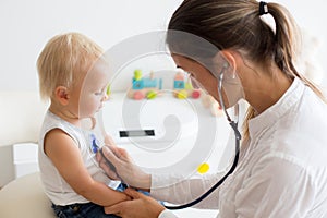 Pediatrician examining baby boy. Doctor using stethoscope to listen to kid