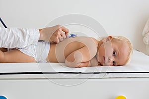 Pediatrician examining baby boy. Doctor using stethoscope to listen to kid