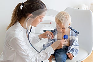Pediatrician examining baby boy. Doctor using stethoscope to listen to kid