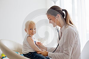 Pediatrician examining baby boy. Doctor using stethoscope to listen to kid