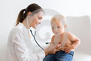 Pediatrician examining baby boy. Doctor using stethoscope to listen to kid