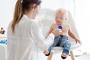 Pediatrician examining baby boy. Doctor using stethoscope to listen to kid