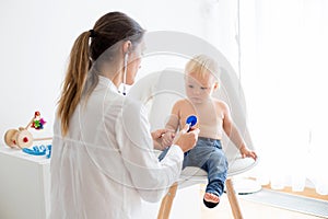 Pediatrician examining baby boy. Doctor using stethoscope to listen to kid