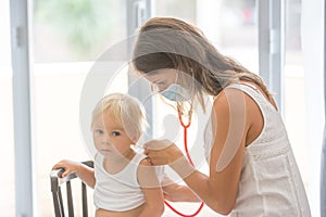 Pediatrician examining baby boy. Doctor using stethoscope to listen to kid and checking heart