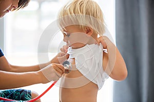 Pediatrician examining baby boy. Doctor using stethoscope to listen to kid and checking heart