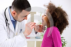 Pediatrician examining cute smiling african girl, throat sick