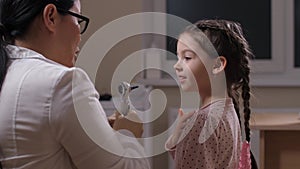 Pediatrician examining ears of joyful little girl