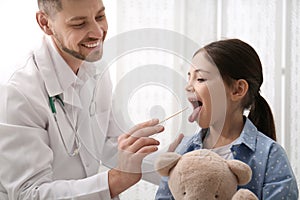 Pediatrician examining girl in office at hospital