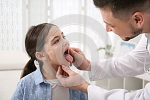 Pediatrician examining girl in office at hospital