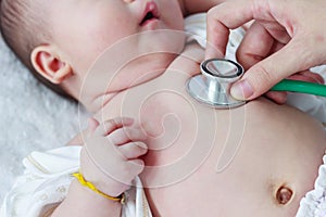 Pediatrician examining infant. Two months baby asian girl lying