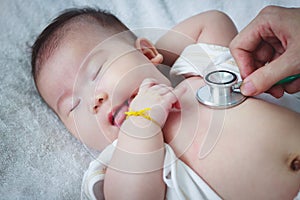 Pediatrician examining infant. Two months baby asian girl lying