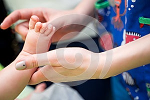 Pediatrician examining little baby in clinic. Closeup of a child& x27;s leg in doctor& x27;s hands.