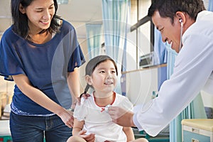 Pediatrician examining little girl , her mother beside her