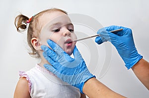 Pediatrician examining little girl`s throat with tongue depressor