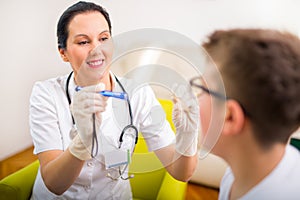 Pediatrician examining teenager throat with tongue depressor