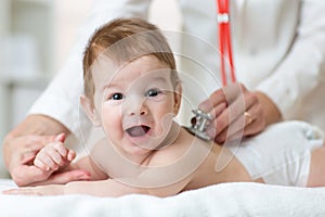 Pediatrician female doctor examines baby with stethoscope checking heart beat