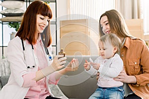 Pediatrician giving spoon dose of medicine liquid drinking syrup to baby patient