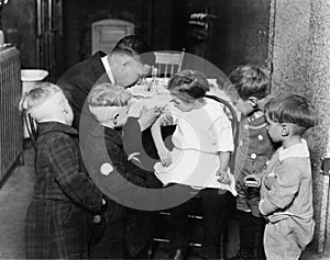 Pediatrician immunizing a little girl while other children are watching