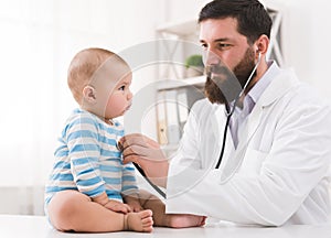 Pediatrician listening to kid`s chest checking heartbeat