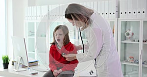 Pediatrician listens to lungs of little girl with stethoscope
