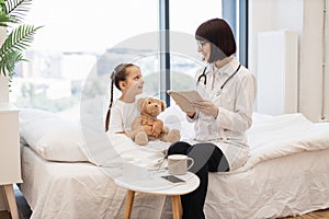 Pediatrician prescribing medicine on tablet for kid at home