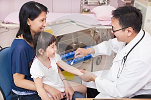 Pediatrician rubbing medication on little girl arm wound