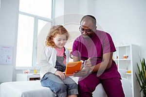 Pediatrician showing cartoon on tablet for his little patient