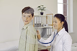 Pediatrician with a stethoscope examining lungs or heartbeat of her little patient