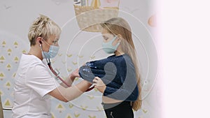 Pediatrician with stethoscope examining young kid girl with blond hair