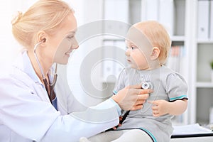 Pediatrician is taking care of baby in hospital. Little girl is being examine by doctor with stethoscope