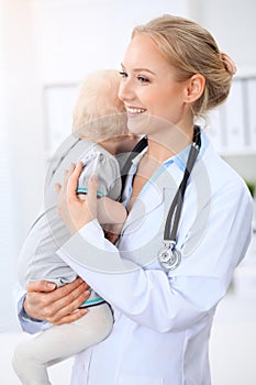 Pediatrician is taking care of baby in hospital. Little girl is being examine by doctor with stethoscope