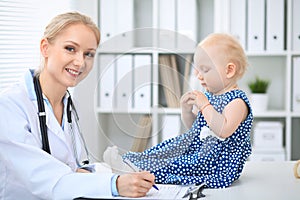 Pediatrician is taking care of baby in hospital. Little girl is being examine by doctor with stethoscope