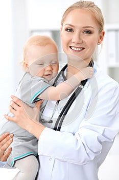 Pediatrician is taking care of baby in hospital. Little girl is being examine by doctor with stethoscope