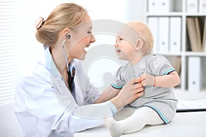 Pediatrician is taking care of baby in hospital. Little girl is being examine by doctor with stethoscope