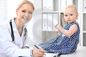 Pediatrician is taking care of baby in hospital. Little girl is being examine by doctor with stethoscope