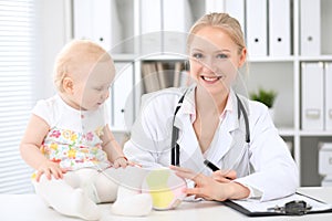 Pediatrician is taking care of baby in hospital. Little girl is being examine by doctor with stethoscope