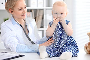 Pediatrician is taking care of baby in hospital. Little girl is being examine by doctor with stethoscope