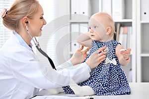 Pediatrician is taking care of baby in hospital. Little girl is being examine by doctor with stethoscope