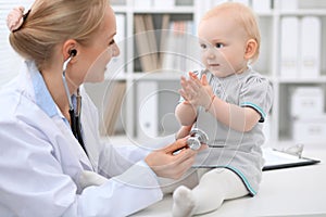 Pediatrician is taking care of baby in hospital. Little girl is being examine by doctor with stethoscope