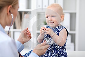 Pediatrician is taking care of baby in hospital. Little girl is being examine by doctor with stethoscope