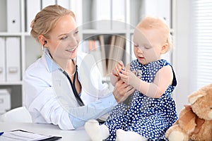 Pediatrician is taking care of baby in hospital. Little girl is being examine by doctor with stethoscope