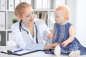 Pediatrician is taking care of baby in hospital. Little girl is being examine by doctor with stethoscope