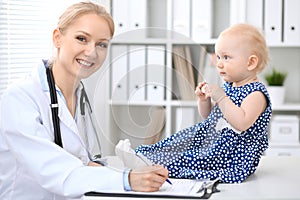 Pediatrician is taking care of baby in hospital. Little girl is being examine by doctor with stethoscope