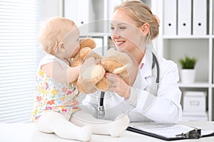 Pediatrician is taking care of baby in hospital. Little girl is being examine by doctor with stethoscope