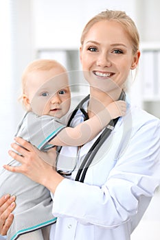 Pediatrician is taking care of baby in hospital. Little girl is being examine by doctor with stethoscope