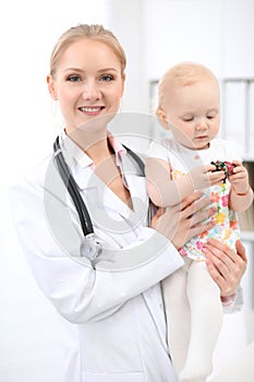 Pediatrician is taking care of baby in hospital. Little girl is being examine by doctor with stethoscope