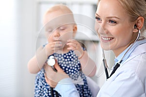 Pediatrician is taking care of baby in hospital. Little girl is being examine by doctor with stethoscope