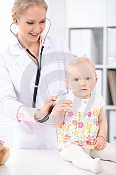 Pediatrician is taking care of baby in hospital. Little girl is being examine by doctor with stethoscope