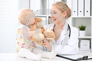 Pediatrician is taking care of baby in hospital. Little girl is being examine by doctor with stethoscope